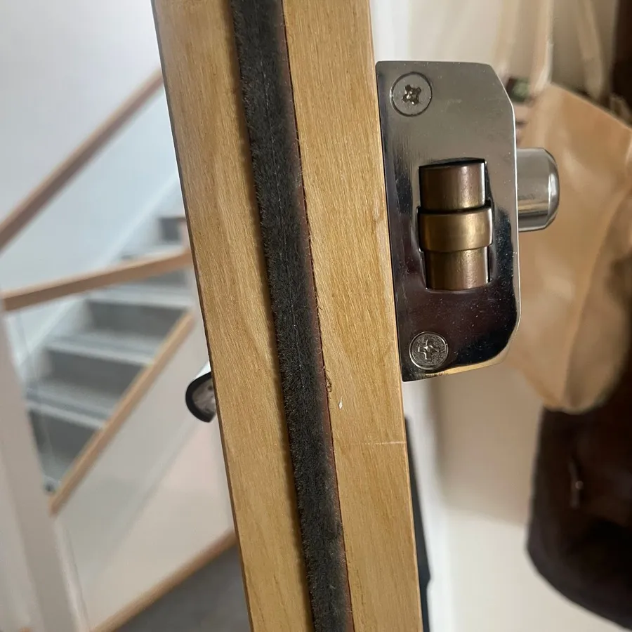 A new deadbolt keep fitted to a flat door frame, communal stairs behind