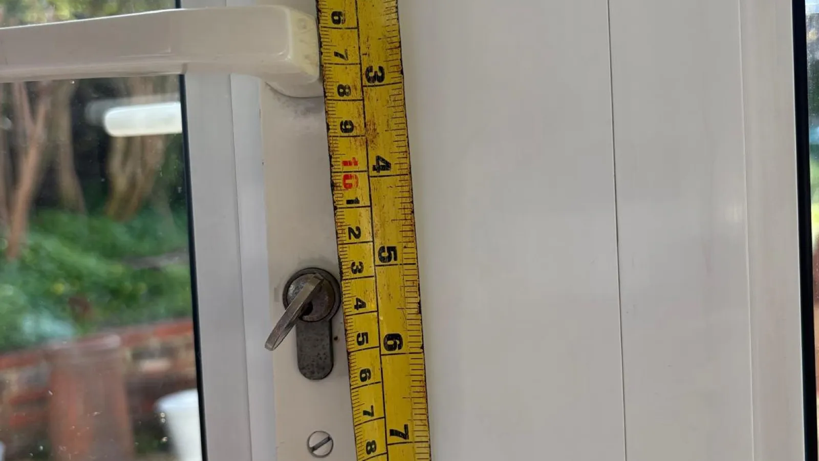 Measuring up a uPVC double door before quoting — the quote is fixed before any work starts
