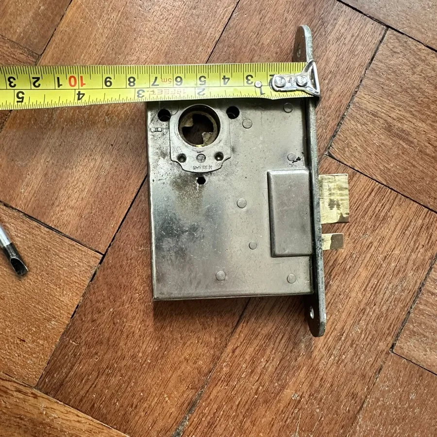 A worn mortice lock case removed from a front door, measured before a like-for-like replacement