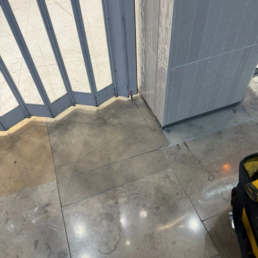 A folding security shutter at a shopfront, tools out during a repair