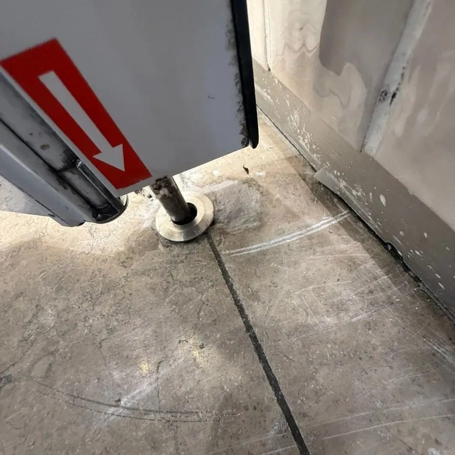 A shutter floor pivot and socket at a shop entrance after refitting